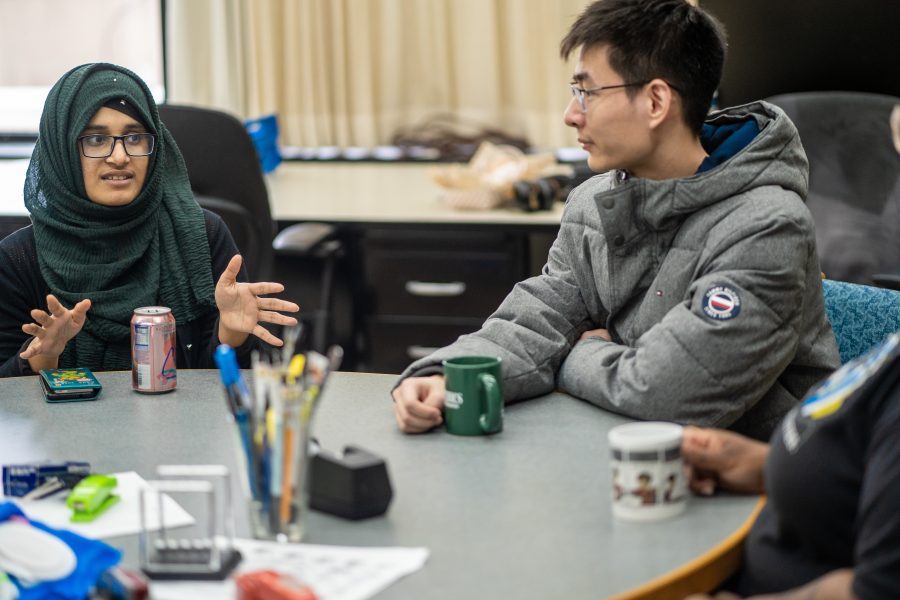 two students talk around a round table.